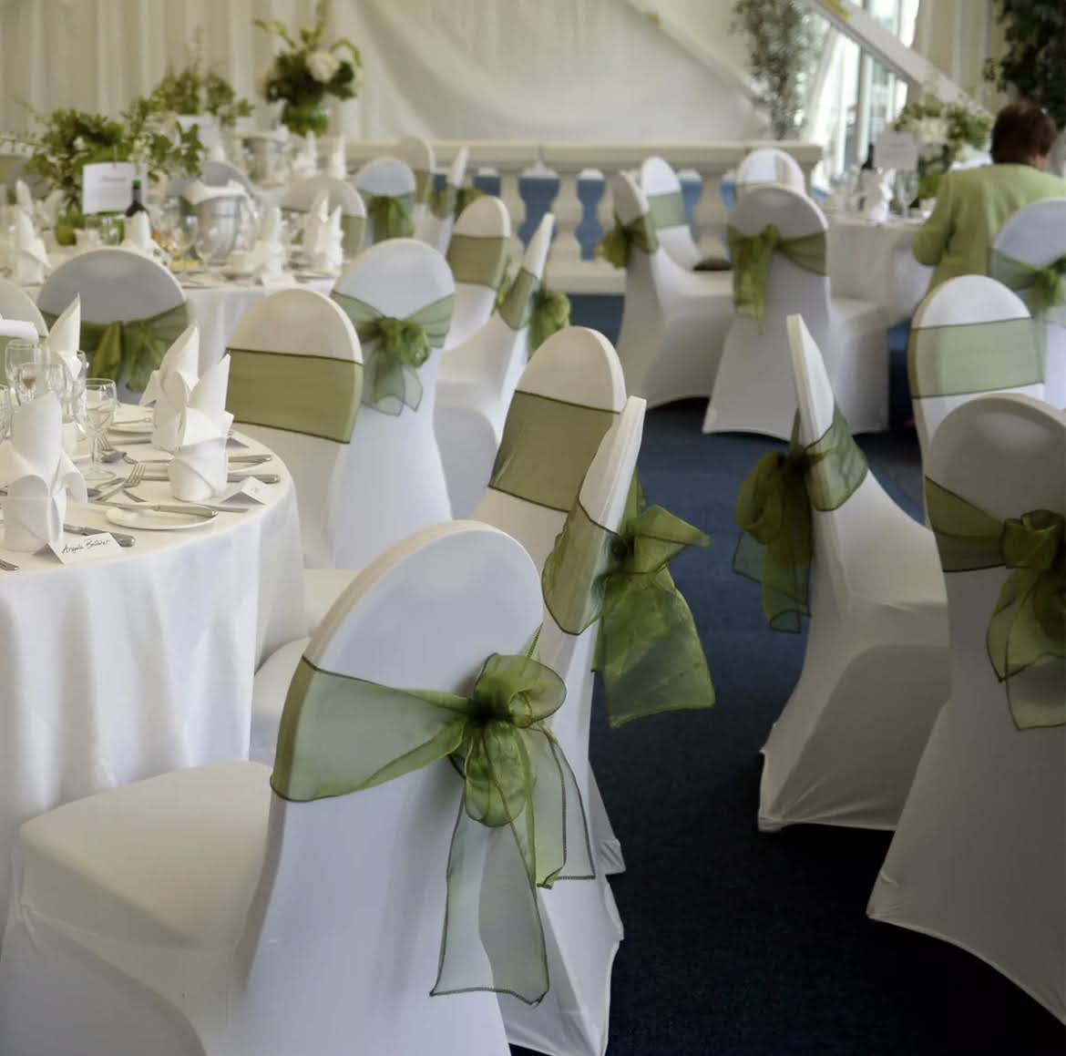 White-covered chairs finished with green organza bows