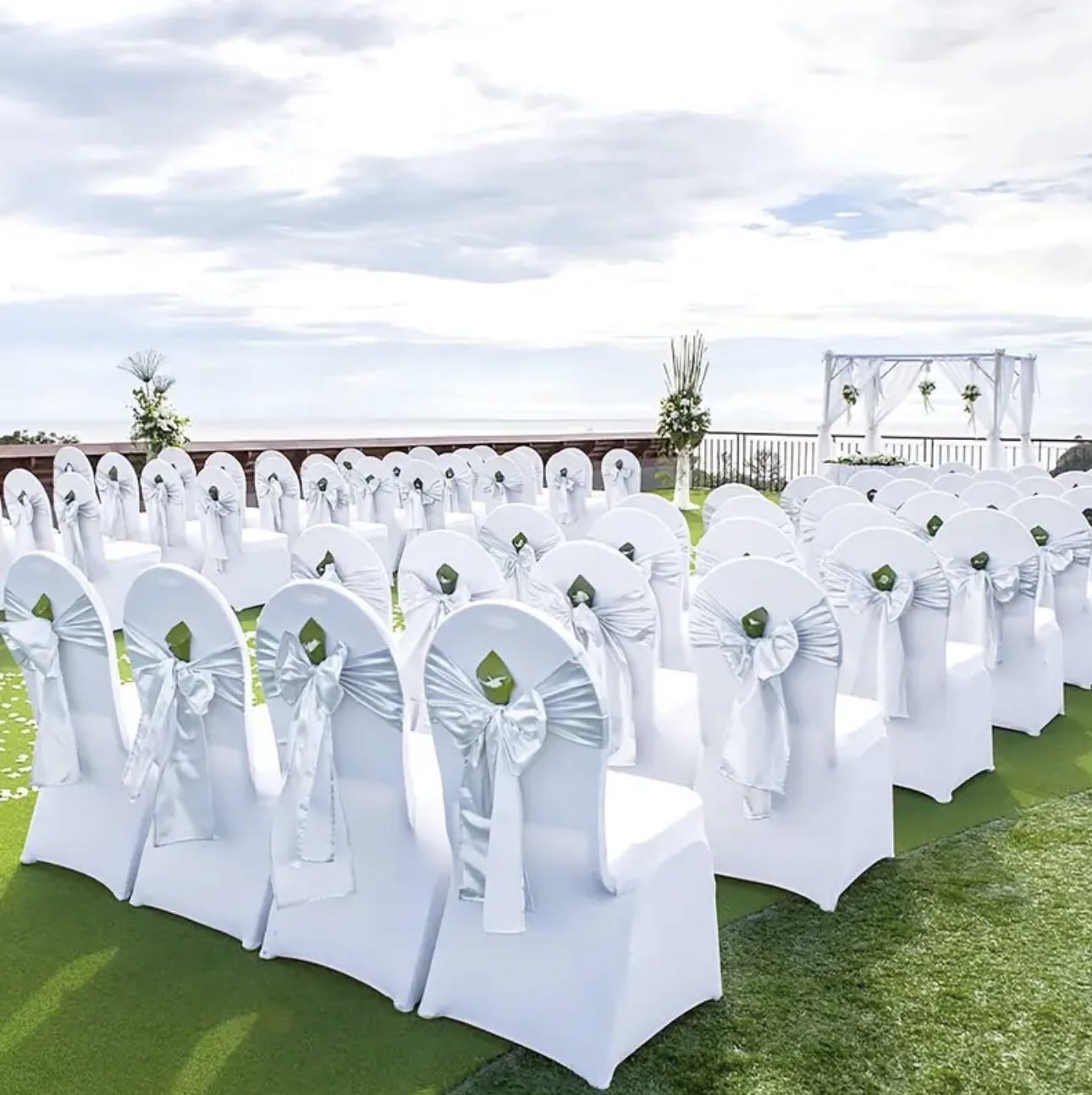 Outdoor wedding ceremony with white covered chairs and decorative bows